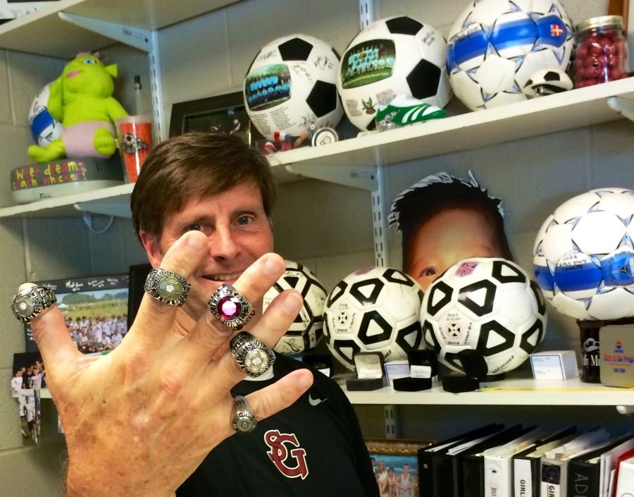 Coach+Tony+Whicker+flaunts+his+five+state+championship+rings.+Girls%E2%80%99+soccer+won+three+of+his+five+state+championships%2C+and+the+boys%E2%80%99+team+won+two.