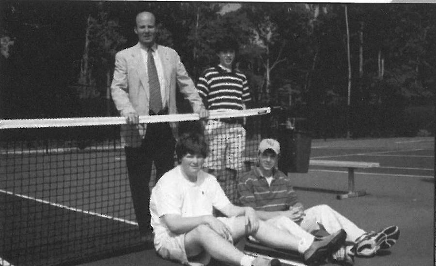 Coach Bill Taylor and	the first	varsity tennis team pose for	a yearbook	picture. The team consisted of one ninth grader, who graduated in 2006, and	two eighth graders, who	graduated the following year.