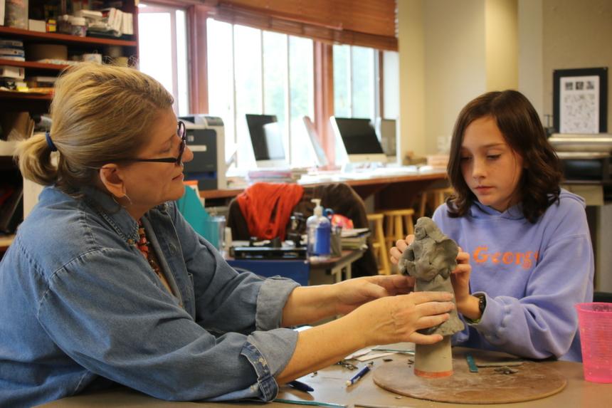 Ms. Rose Doherty helps sixth grader Maggie Wilson  with a sculpture. 