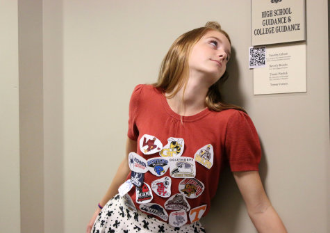 Senior Caroline Cannon drowns in the logos of the schools she is applying to while wondering which one will have her name on it in the senior dining hall. Other seniors have already put their signs up on the windows displaying their college selection.