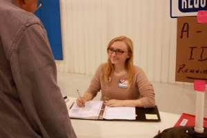 Senior Juliana Wall greets a voter as she signs him in the registrar book.  Over 1,030 people came through the doors on Election Day. 