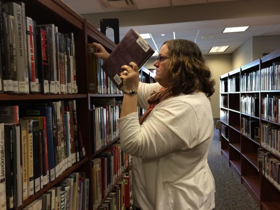 Mrs. Leah Allison works to improve the library by putting away a book that was put in the wrong spot, making it available for students to find easily. The library has been a fundamental part of the St. Georges community since its founding, hosting a quiet place for studying and reading.