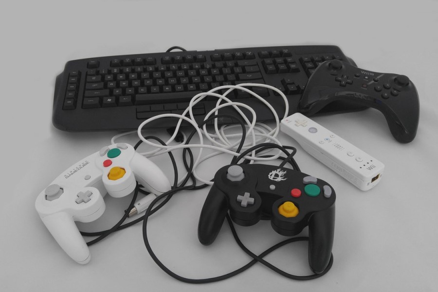 A collection of Grant Webbs controllers for various gaming systems are photographed together. He purchased specific controllers, as they suit some games better than the others.