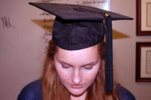 A student poses in a cap and gown. SIS alone determined graduation with distinction this year. 