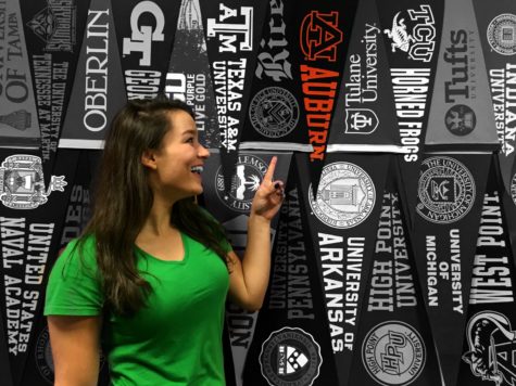 Junior Kate Seabrook points at an Auburn University banner. Some students have already decided which college they want to attend.