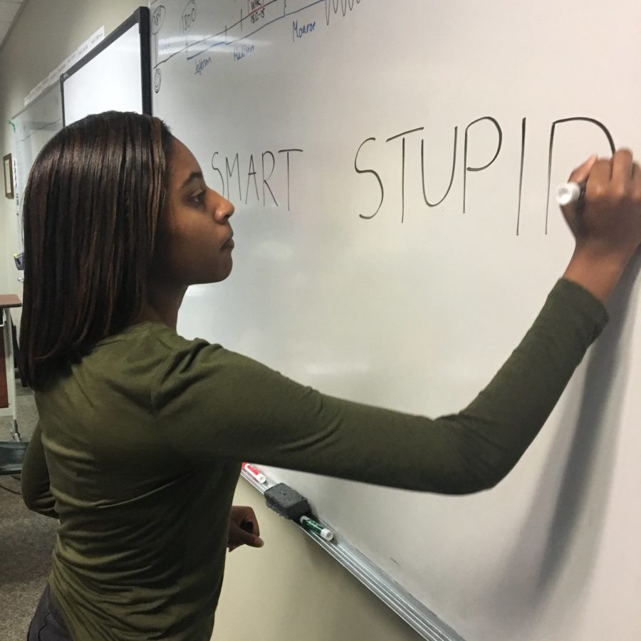 Junior Lauren Purdy writes smart or stupid on a white board. The debate over the definition of dyslexia has evolved over time and should eventually reach a middle ground.