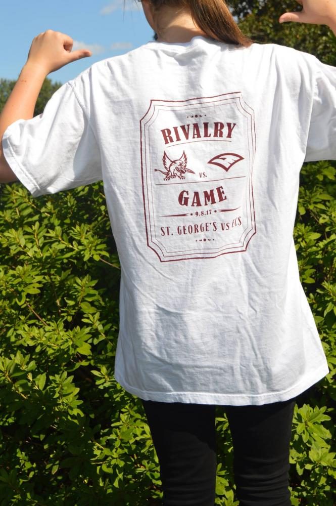 Student+poses+with+new+rivalry+t-shirt.+The+Bleacher+Creatures+partnered+with+Agape+North+to+make+a+white+t-shirt+that+students+can+wear+to+the+Fine+Arts+Tailgate+color+rally+before+the+game+Friday.+