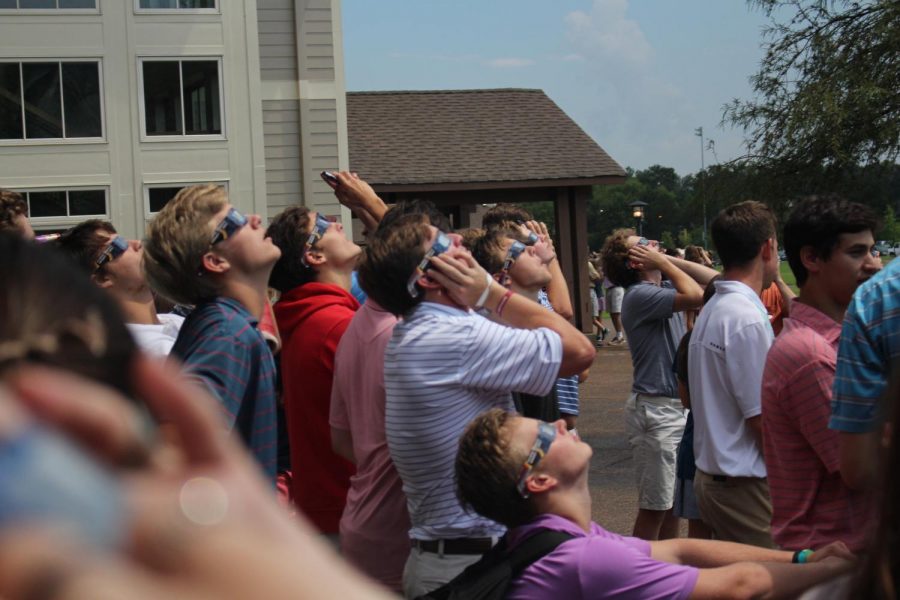 A cluster of high school boys gathers to view the eclipse through their glasses.