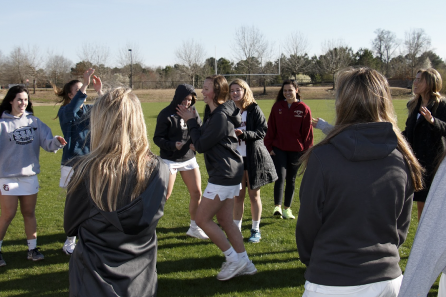 The girls lacrosse team dances before a practice. The team recently added Coach Rachel Smith to their staff.