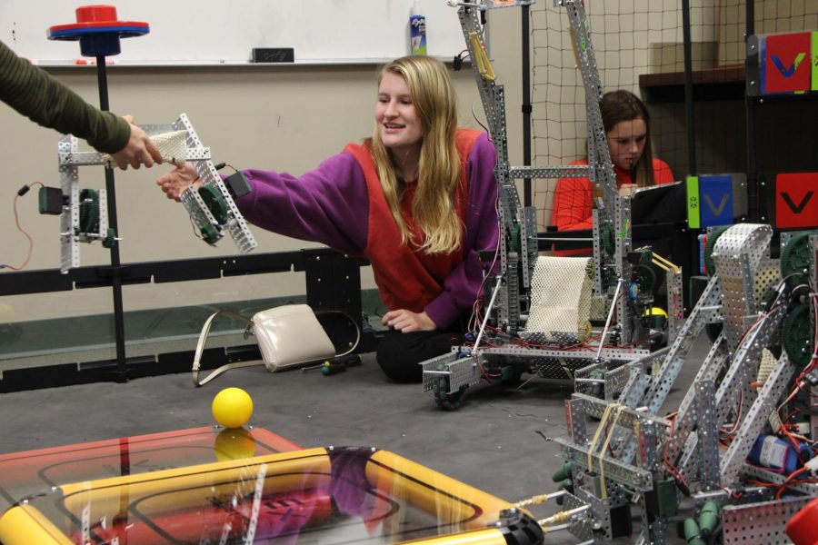 Junior+Elizabeth+Crane+smiles+as+she+receives+a+robot+base.+The+team+collaborated+on+the+field+while+preparing+for+the+tournament.