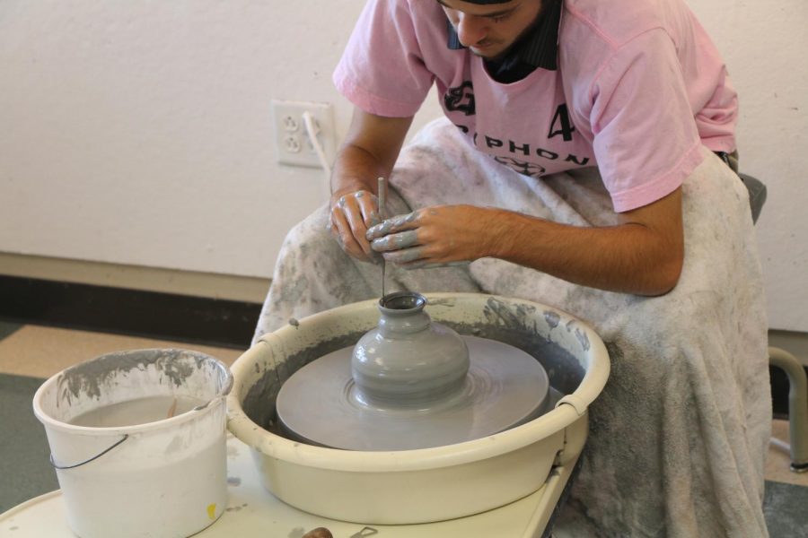 Senior Kelan Parsons trims his newly made pot. The pottery class has eight wheels and other clay-working stations.