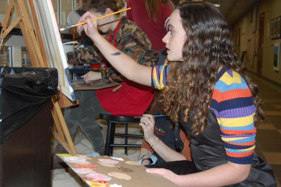 Student artist Chloe Lewis paints at the art show. This display was one of many student showcases.