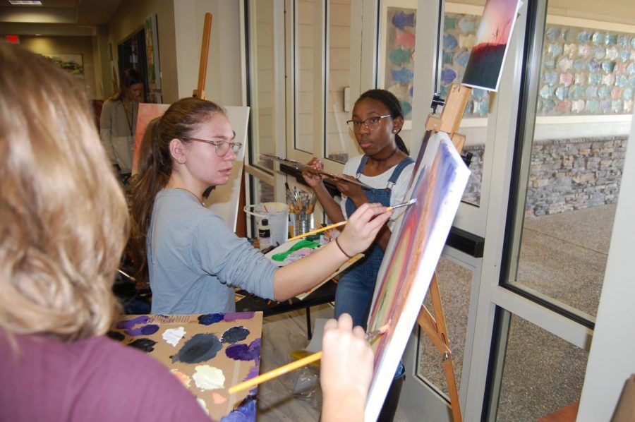 Sophomore Caroline Higley works with her group to paint a sunset at the Art Show on Nov 7. Two groups of students formed to work on the live art painting.