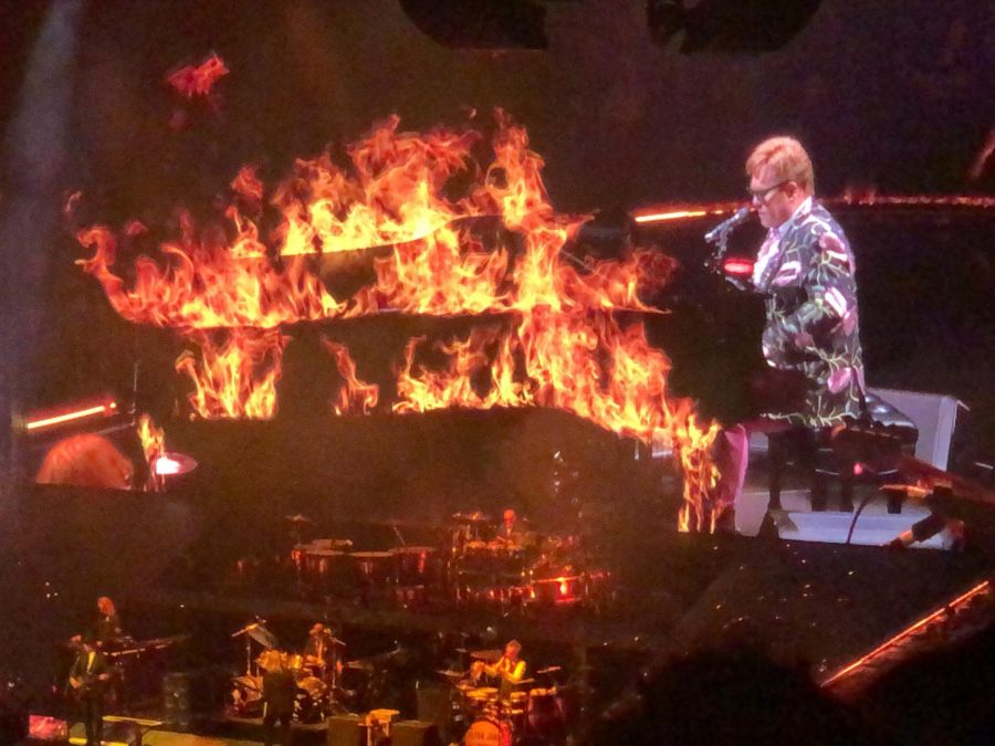 Elton John enthusiastically plays piano for his final Memphis audience. An effect on the screen shows his piano on fire.