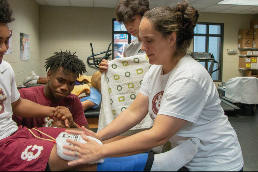 Mrs. Tina Cole, the head athletic trainer at St. George’s, works with junior Khalil Moore while junior Zion Boggan provides moral support. Many athletes at St. George’s have
found that the athletic resources available can provide much needed support during lengthy
recoveries.