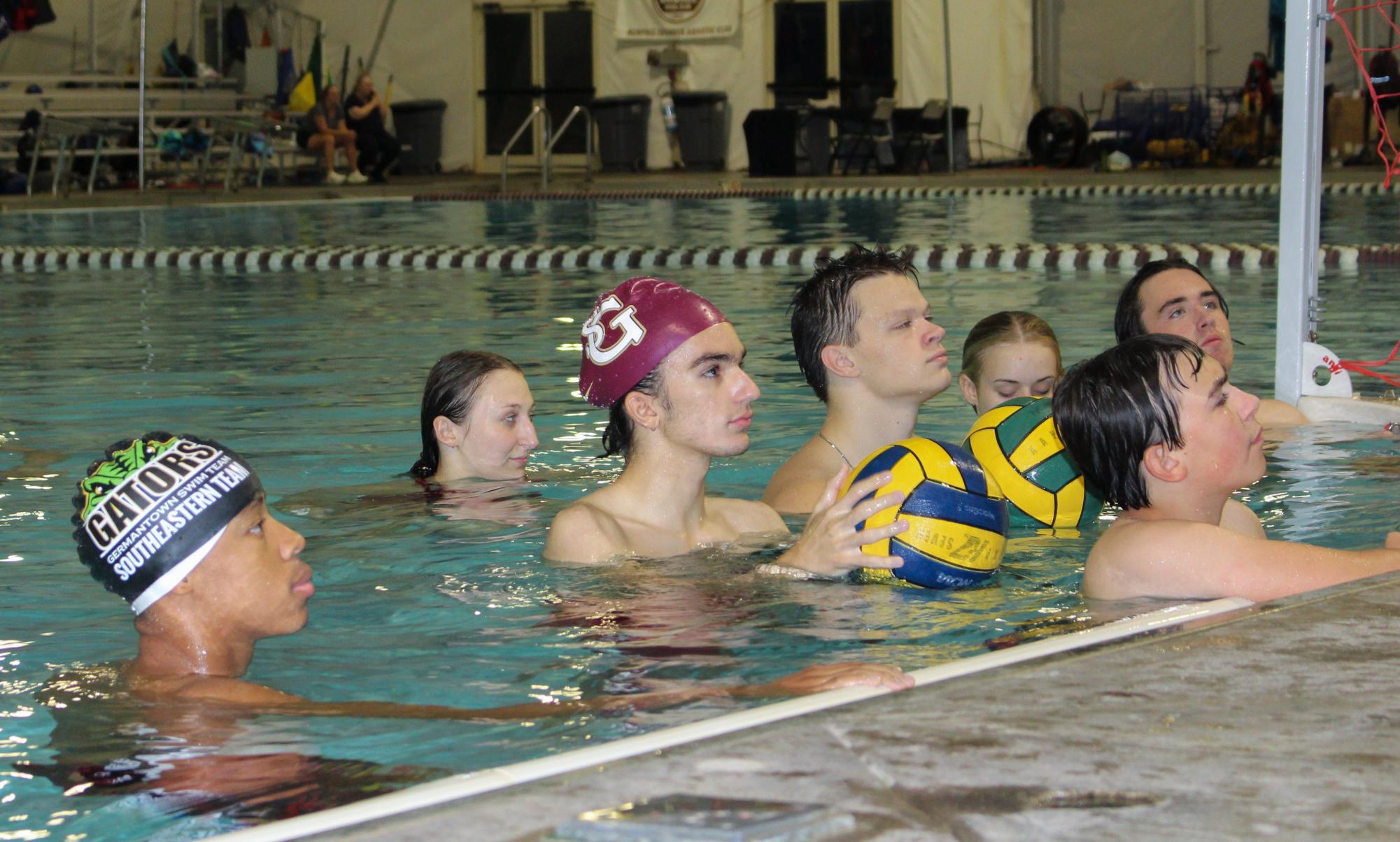 The water polo team listens to coaches during practice for instruction. 