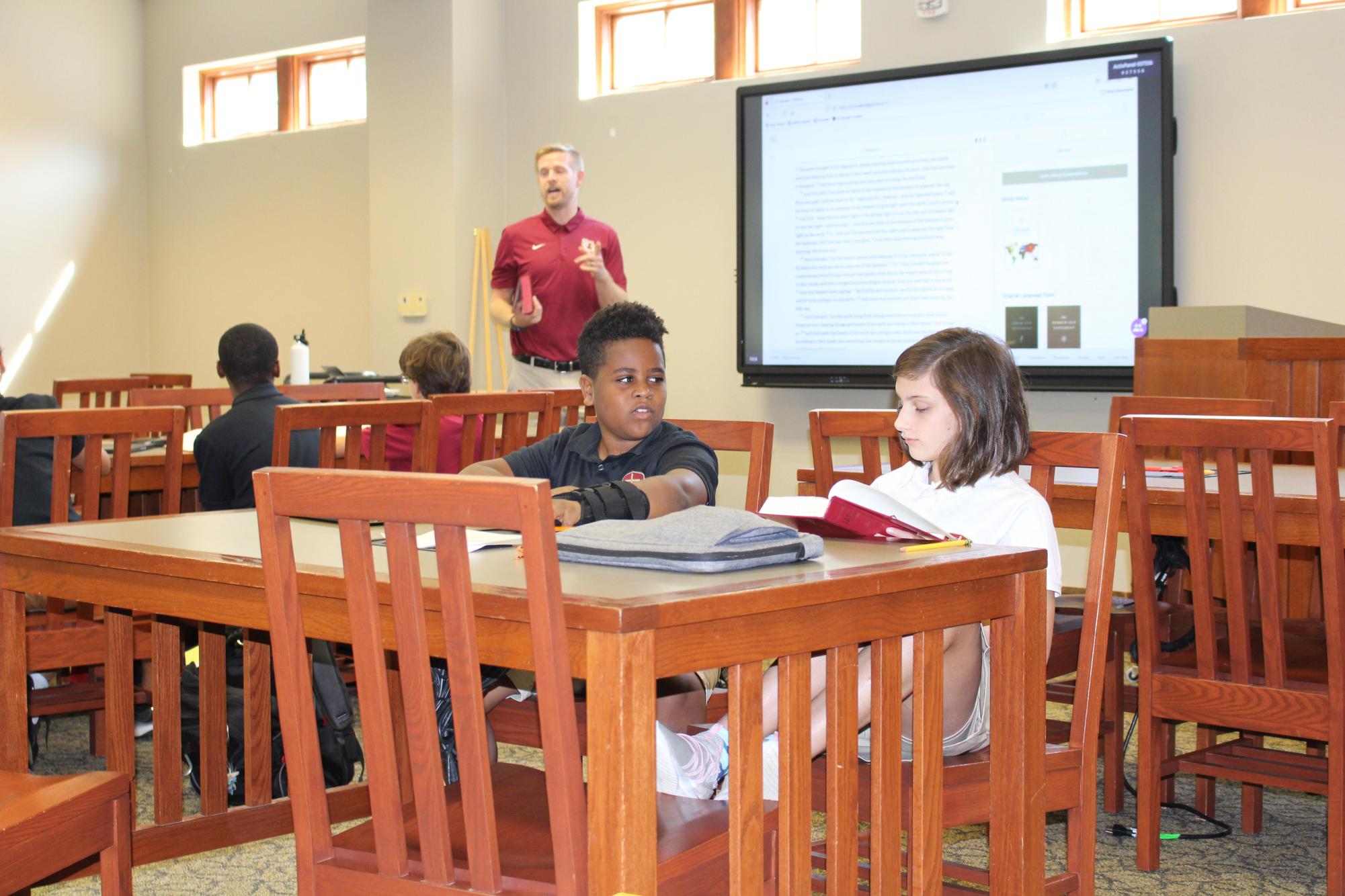 Mr. Nick Whicker uses the Learning Commons for his middle school religion class, where students are collaborating.