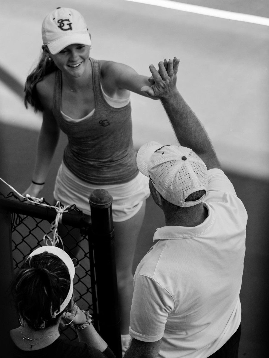 Senior Ava Magness high-fives Coach Jay Walpole after winning her match against an ECS tennis player on senior day at the Lightman Tennis Center on Tuesday, April 7, 2026. Magness served as a captain for the varsity girls tennis team.
